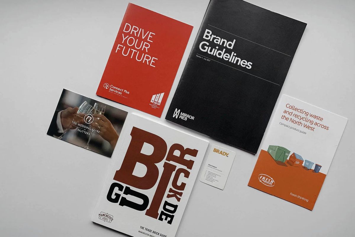 Printed brand guidelines, brochures and business cards laid out on a desk
