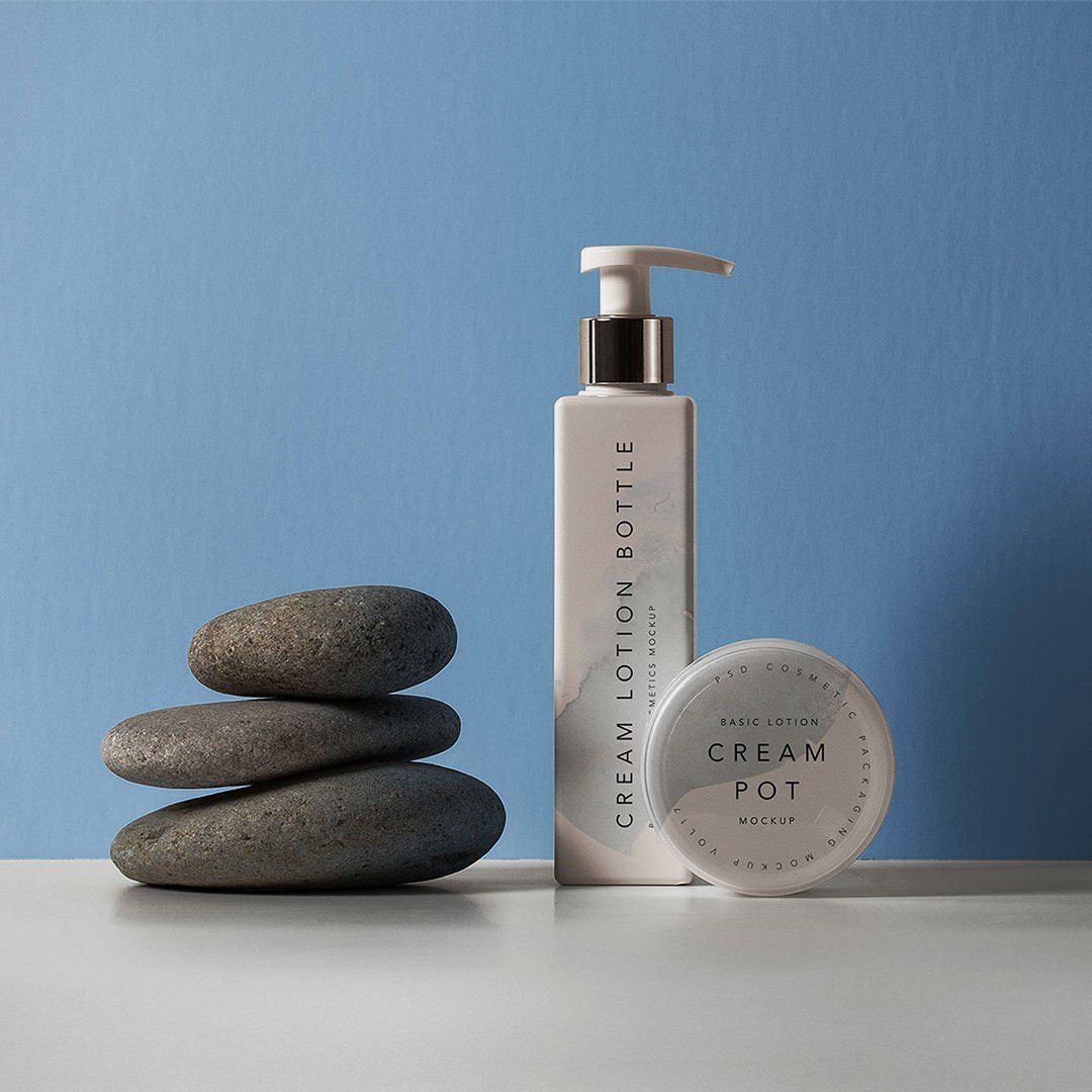 Product photograph of a lotion bottle and jar beside stacked stones
