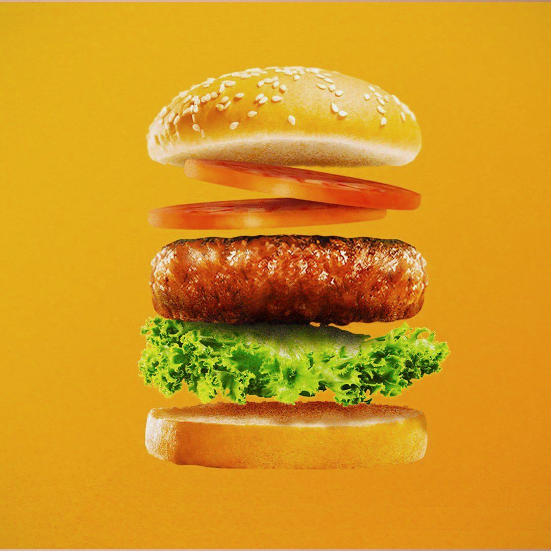 A burger with its layers floating apart on an orange background