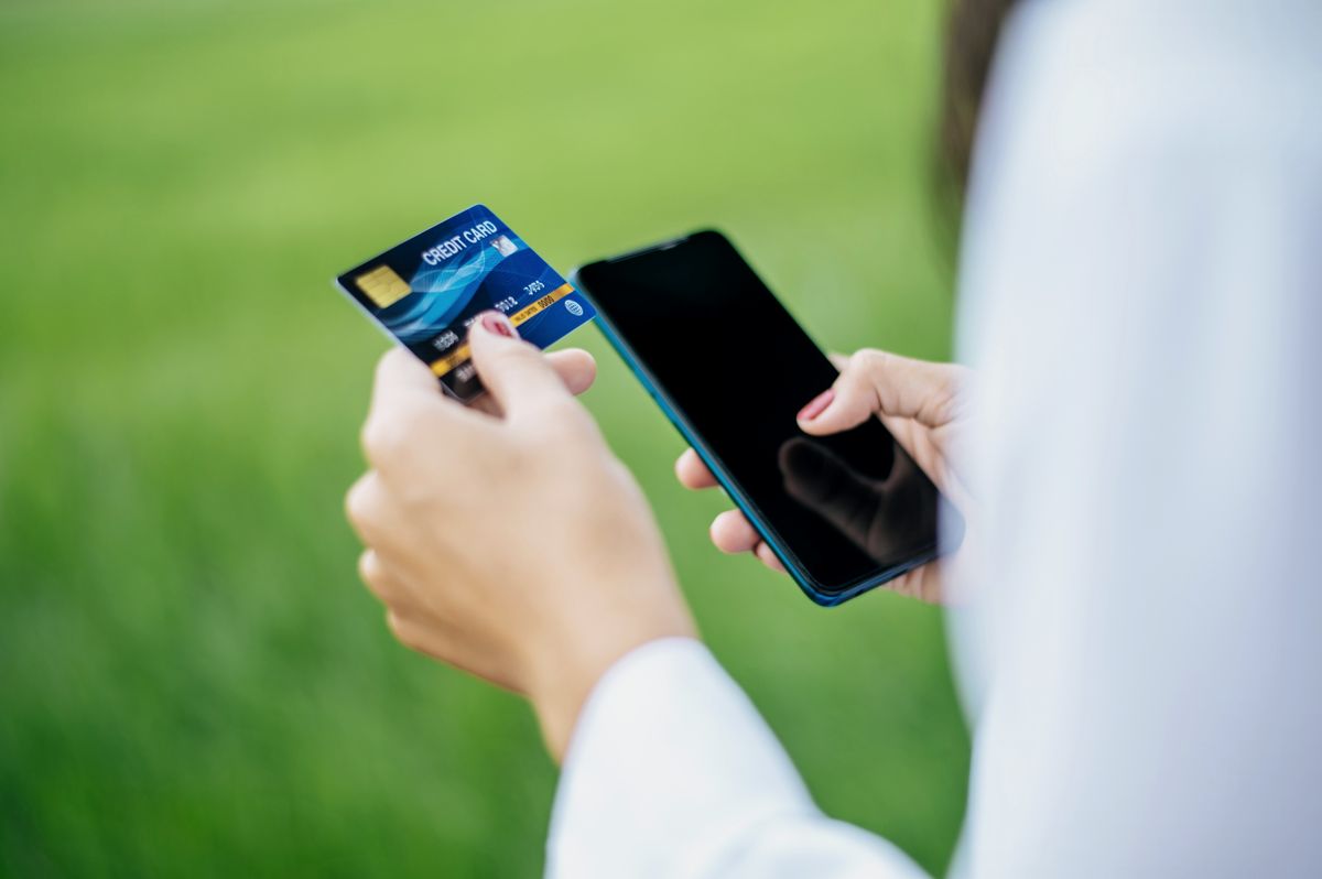 A hand paying by card beside a smartphone